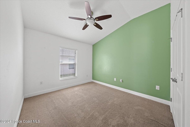 empty room featuring a textured ceiling, carpet floors, vaulted ceiling, and ceiling fan