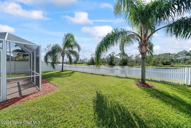 view of yard featuring glass enclosure and a water view