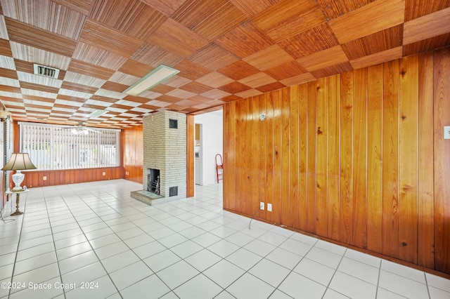 tiled spare room featuring wood ceiling, wood walls, and a brick fireplace