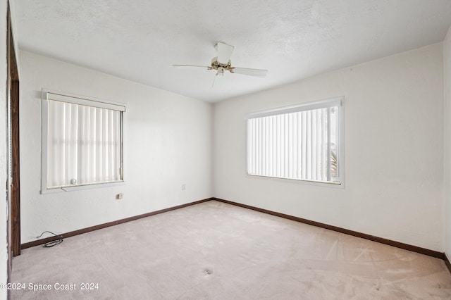 unfurnished room featuring ceiling fan, light colored carpet, and plenty of natural light