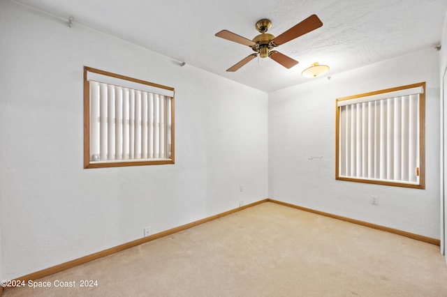 carpeted spare room with ceiling fan and a textured ceiling