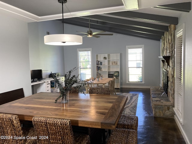 dining room featuring vaulted ceiling with beams, ceiling fan, a healthy amount of sunlight, and a stone fireplace