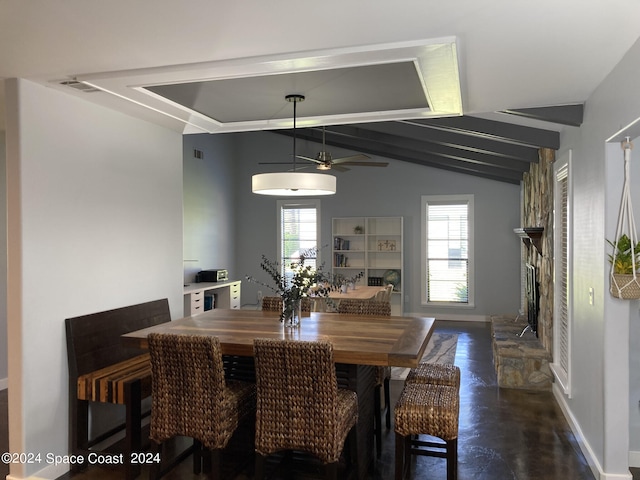 dining area with ceiling fan, vaulted ceiling with beams, and a fireplace