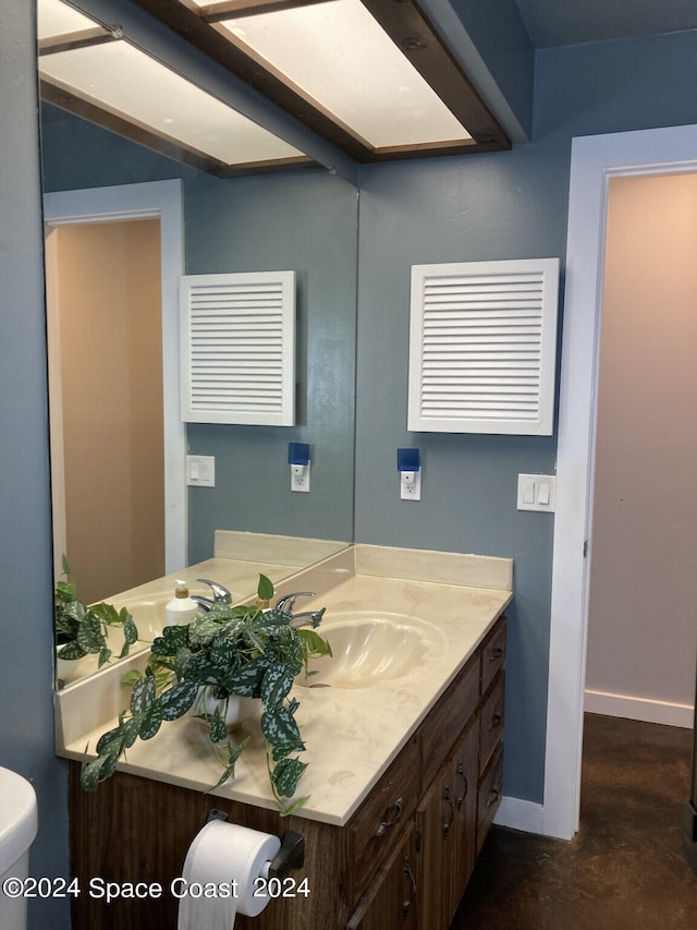 bathroom with vanity, toilet, and concrete flooring