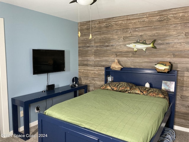 bedroom featuring wooden walls, ceiling fan, and carpet floors