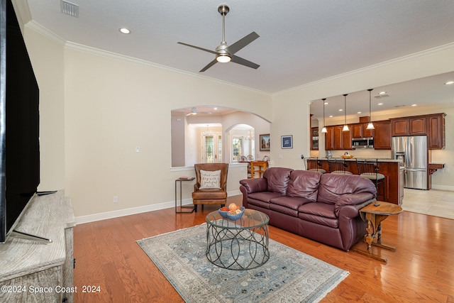 living room with light hardwood / wood-style flooring, a textured ceiling, ceiling fan, and crown molding