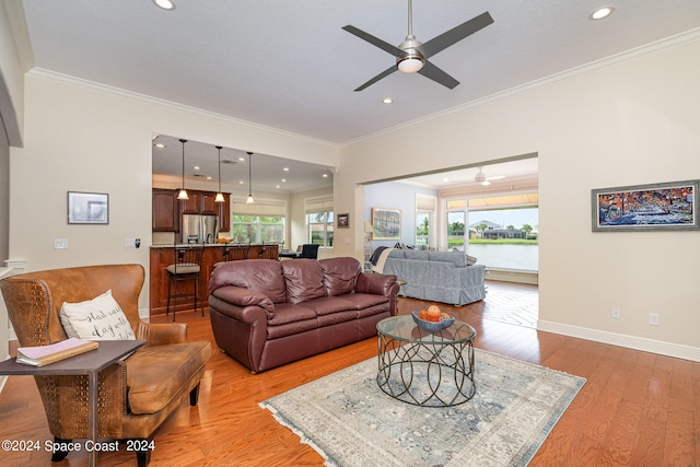 living room with a water view, light hardwood / wood-style floors, ornamental molding, and ceiling fan