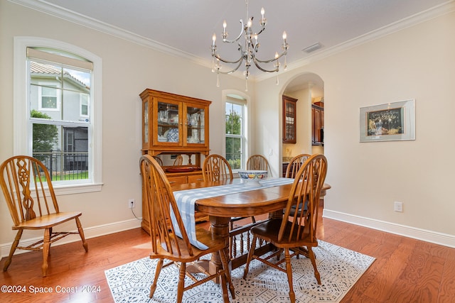 dining space featuring an inviting chandelier, hardwood / wood-style floors, and crown molding