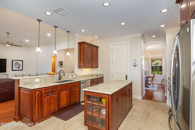 kitchen with sink, ceiling fan with notable chandelier, a kitchen island, appliances with stainless steel finishes, and decorative light fixtures