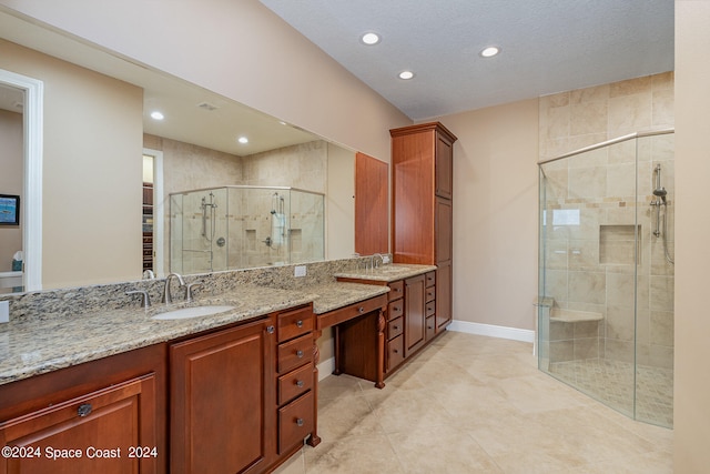 bathroom with vanity, a textured ceiling, and a shower with door