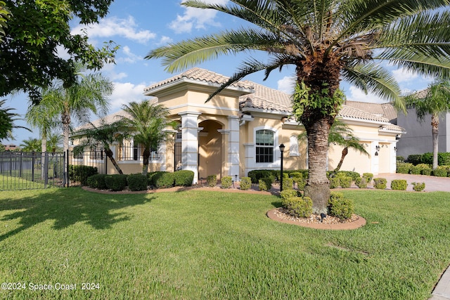 mediterranean / spanish-style home featuring a front yard and a garage