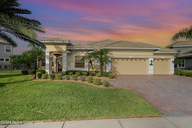 mediterranean / spanish-style home featuring a garage and a yard