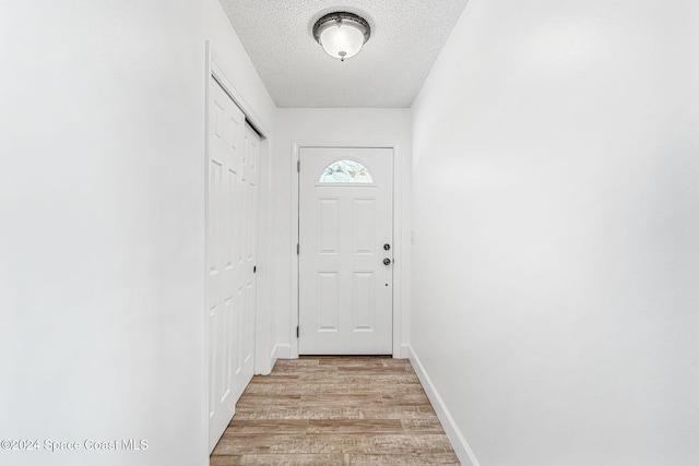 doorway featuring light hardwood / wood-style floors and a textured ceiling