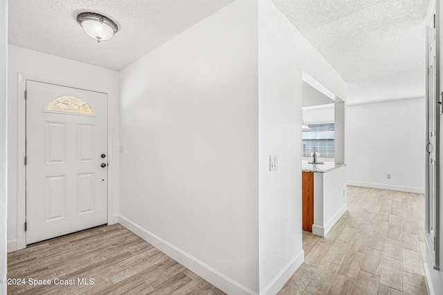 entryway with a textured ceiling and light hardwood / wood-style floors