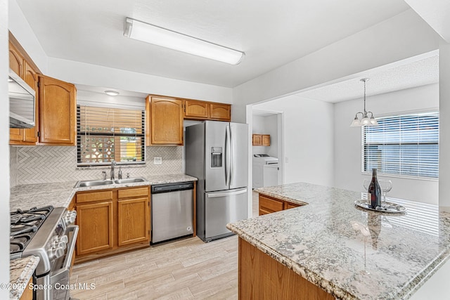 2415 Stanford Dr, Cocoa, FL 32926 - kitchen with appliances with stainless steel finishes, washing machine and clothes dryer, a sink, light wood-style flooring, and tasteful backsplash