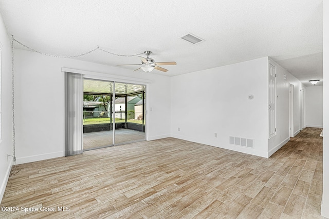 empty room featuring a textured ceiling, light hardwood / wood-style floors, and ceiling fan