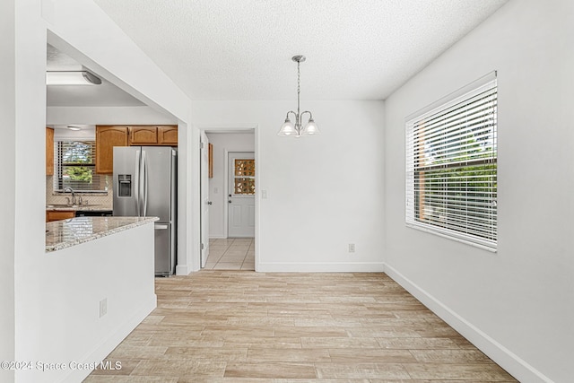 2415 Stanford Dr, Cocoa, FL 32926 - unfurnished dining area featuring a sink, a textured ceiling, a chandelier, light wood finished floors, and baseboards