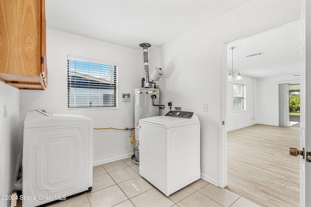 laundry area with cabinets, washer and dryer, a healthy amount of sunlight, and water heater