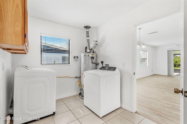 2415 Stanford Dr, Cocoa, FL 32926 - laundry area with cabinet space, washing machine and dryer, gas water heater, baseboards, and light tile patterned flooring