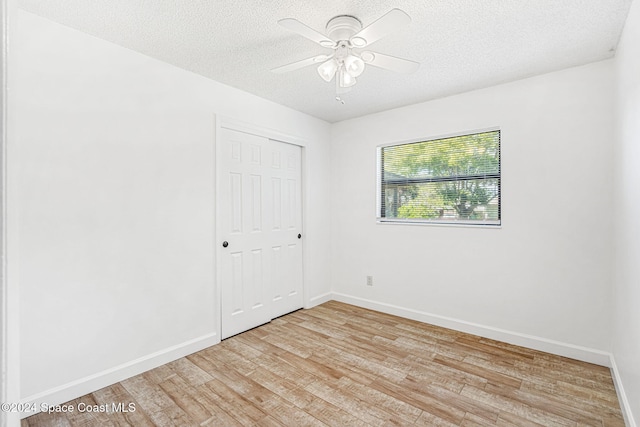2415 Stanford Dr, Cocoa, FL 32926 - unfurnished bedroom with light wood-style floors, a textured ceiling, baseboards, a closet, and a ceiling fan