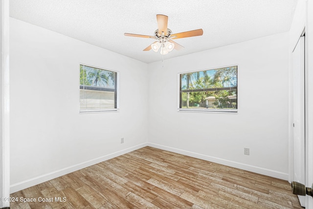 2415 Stanford Dr, Cocoa, FL 32926 - unfurnished bedroom with multiple windows, light wood finished floors, baseboards, and a textured ceiling