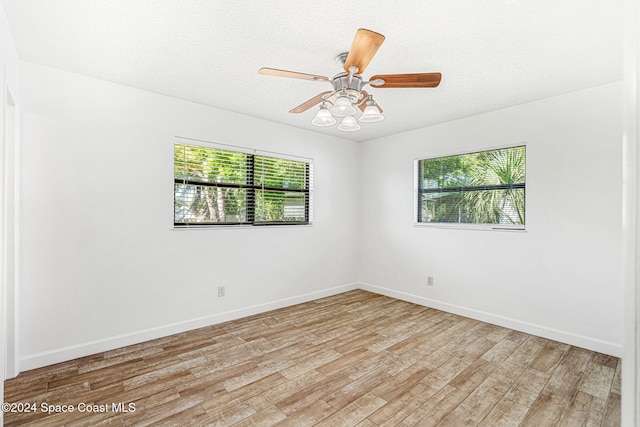 spare room with a textured ceiling, light wood-type flooring, plenty of natural light, and ceiling fan