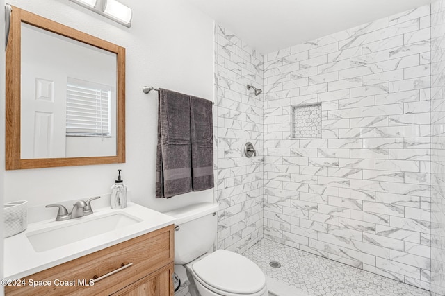 bathroom featuring tiled shower, vanity, and toilet