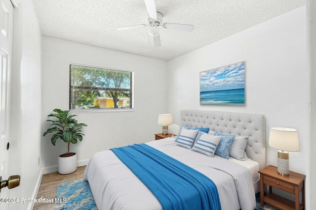 bedroom with ceiling fan, wood-type flooring, and a textured ceiling