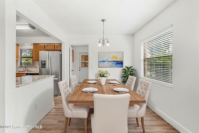 dining space featuring light hardwood / wood-style flooring, a chandelier, a textured ceiling, and sink