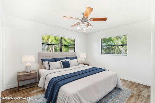 bedroom with a textured ceiling, light wood-type flooring, and ceiling fan