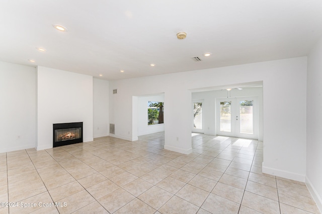 unfurnished living room with ceiling fan, light tile patterned floors, and french doors