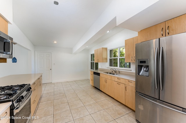 kitchen with light brown cabinets, sink, vaulted ceiling, appliances with stainless steel finishes, and light tile patterned flooring