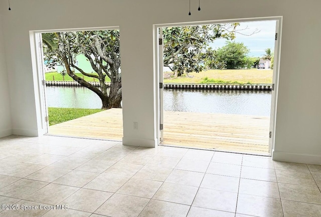 doorway to outside with a water view, light tile patterned floors, and a wealth of natural light