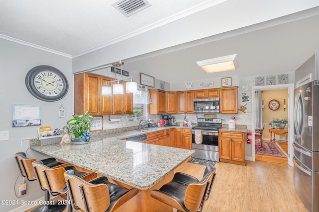 kitchen featuring sink, kitchen peninsula, hanging light fixtures, a kitchen breakfast bar, and stainless steel appliances