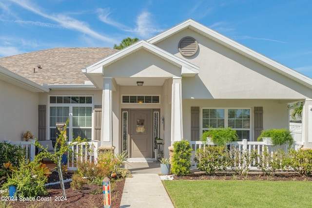 view of exterior entry featuring a yard and covered porch