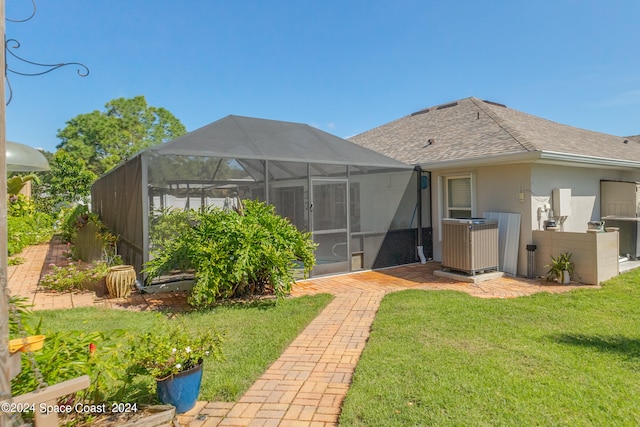 rear view of property with a lanai, a patio, and a lawn