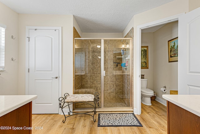 bathroom with walk in shower, vanity, hardwood / wood-style floors, and toilet