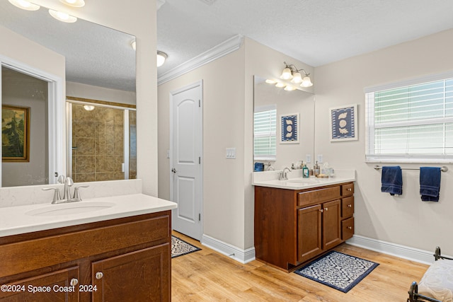 bathroom featuring vanity, a textured ceiling, walk in shower, hardwood / wood-style flooring, and ornamental molding