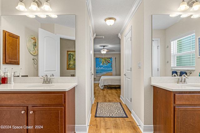 bathroom with vanity, a textured ceiling, wood-type flooring, ceiling fan, and ornamental molding