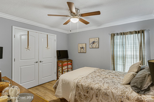 bedroom with light hardwood / wood-style floors, a closet, a textured ceiling, crown molding, and ceiling fan