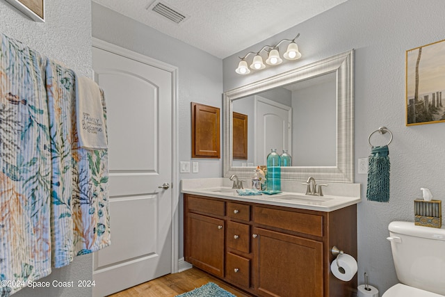 bathroom featuring a textured ceiling, hardwood / wood-style flooring, vanity, and toilet