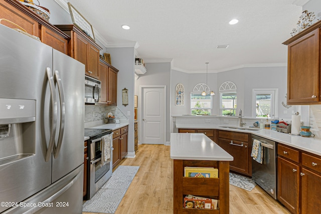 kitchen with appliances with stainless steel finishes, hanging light fixtures, light hardwood / wood-style floors, a center island, and sink