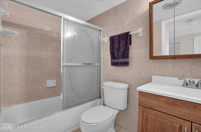 full bathroom with tile walls, vanity, shower / bath combination with glass door, toilet, and tile patterned floors