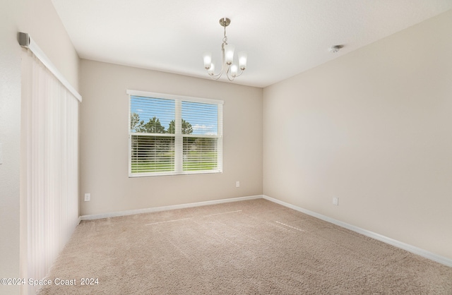 unfurnished room with a notable chandelier and carpet