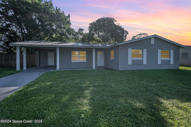 single story home featuring a carport and a lawn