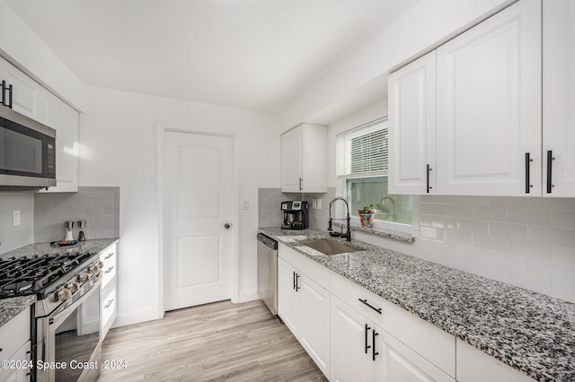 kitchen featuring decorative backsplash, sink, white cabinetry, and stainless steel appliances