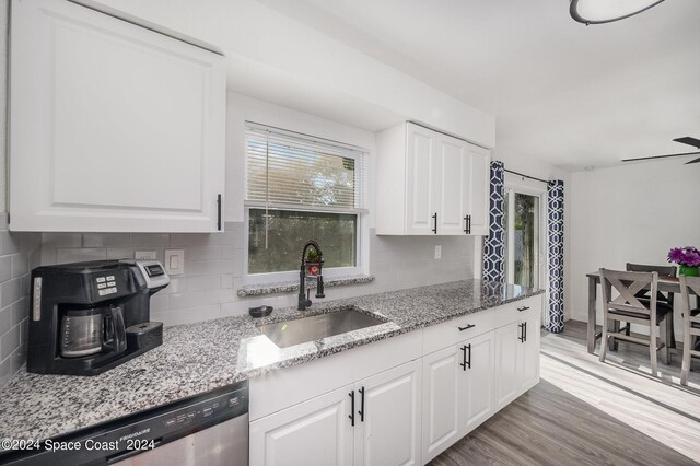 kitchen with dishwasher, white cabinetry, tasteful backsplash, sink, and light stone counters