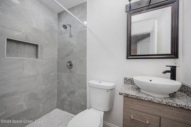 bathroom featuring vanity, toilet, and a tile shower