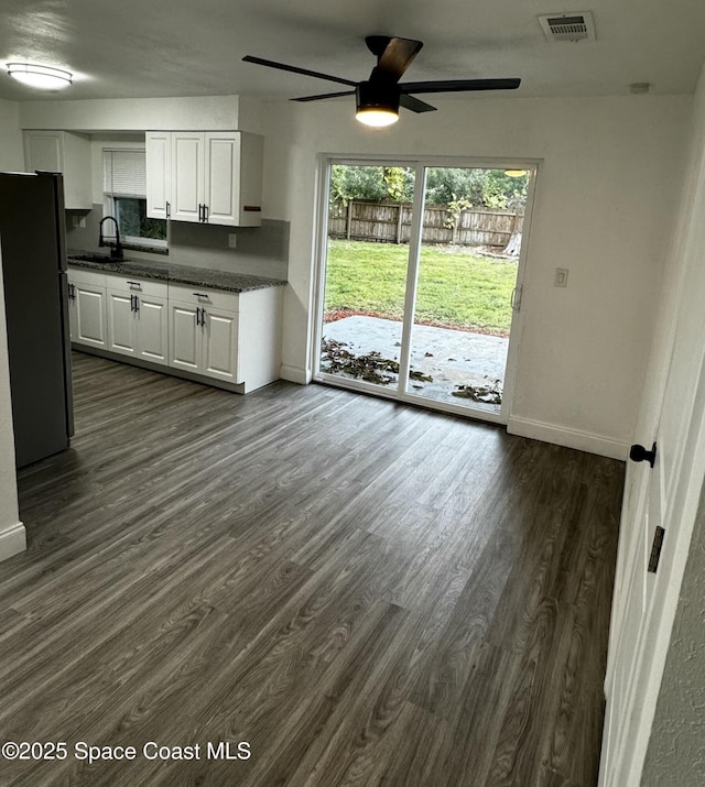 kitchen with dark wood-type flooring, sink, white cabinetry, and stainless steel refrigerator