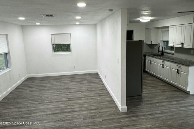 kitchen with sink, white cabinetry, dark hardwood / wood-style floors, and stainless steel refrigerator